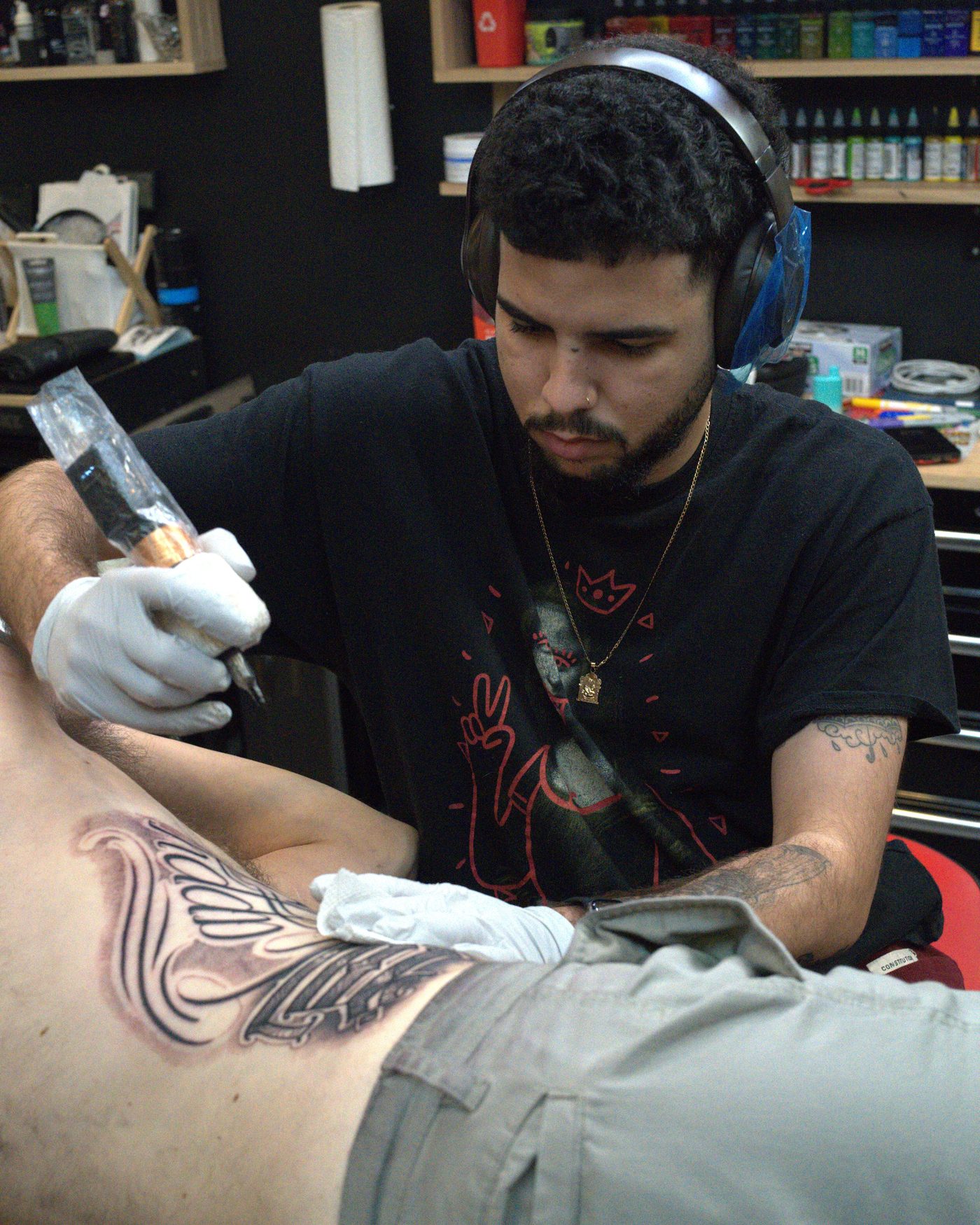Antwan Rodriguez tattooing a black and gray ornamental piece on a client's ribs at Wooden Heart Tattoo, West Palm Beach FL